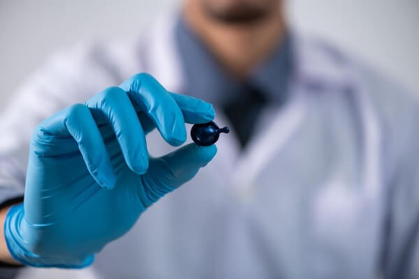 Der Arzt mit blauen sterilen Handschuhen hält eine bionische Knochenkugel